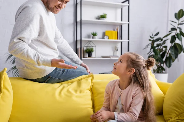 Mann Zeigt Mit Der Hand Auf Lächelnde Tochter Auf Couch — Stockfoto