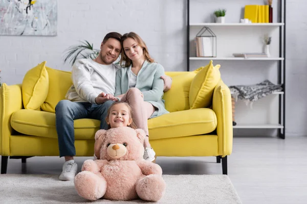 Cheerful Girl Holding Soft Toy Parents Blurred Home — Stock Photo, Image