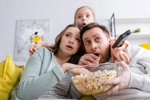 Patlamış mısırlı korkmuş aile kanepede film izliyor. 