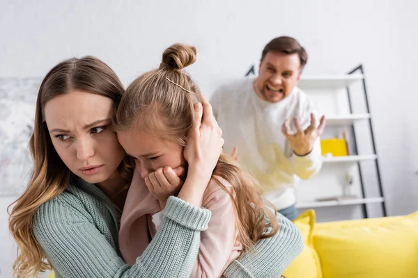 Vrouw Knuffelen Dochter Terwijl Man Schreeuwen Wazig Achtergrond — Stockfoto