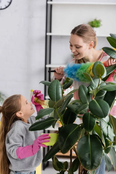 用粉刷和植物在母亲身边拿着抹布和洗涤剂微笑的孩子 — 图库照片
