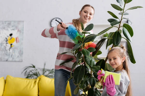 Chica Sonriente Sosteniendo Detergente Trapo Cerca Madre Planta — Foto de Stock