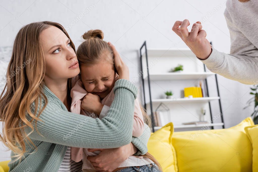 Angry man standing near scared kid and wife 