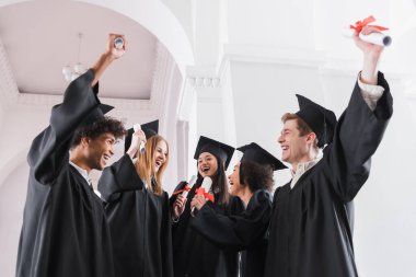 Üniversitede diplomalı neşeli çok ırklı mezunlar 