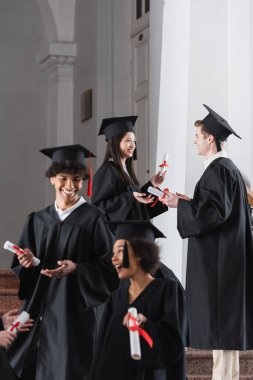 Asyalı mezun üniversiteden bir arkadaşıyla konuşuyor. 