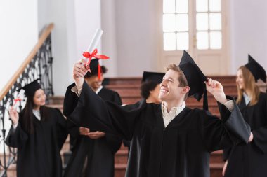 Çok ırklı öğrencilerin yanında diplomaya bakan mutlu bir bekar. 