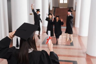 Üniversitede geçmişi bulanık, arkadaşlarının yanında diploma tutan bir öğrenci. 