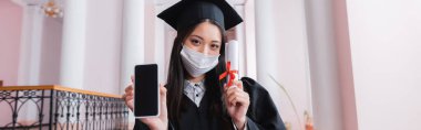 Tıp maskesi takan Asyalı mezun elinde boş ekranlı ve diplomalı akıllı telefon, afiş 