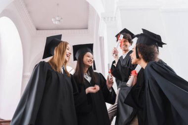 Gülümseyen ırklar arası mezunların üniversite koridorunda diplomaları olması düşük bir bakış açısı. 