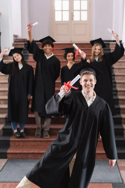 Szczęśliwy Absolwent Gospodarstwa Dyplom Pobliżu Międzyrasowych Przyjaciół Sukienki Akademickie — Zdjęcie stockowe