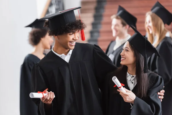 African American Graduate Hugging Asian Friend Diploma — Stock Photo, Image