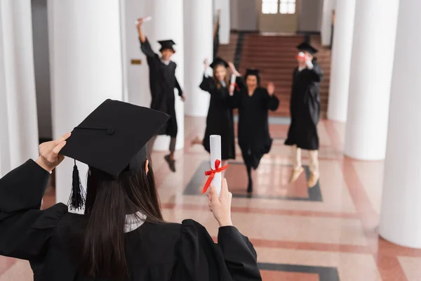 Student Držící Diplom Blízkosti Rozmazané Přátele Rozmazaném Pozadí Univerzitě — Stock fotografie