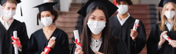 친구들의 졸업장을 가리켜서 의학용 마스크를 아시아 현수막 — 스톡 사진