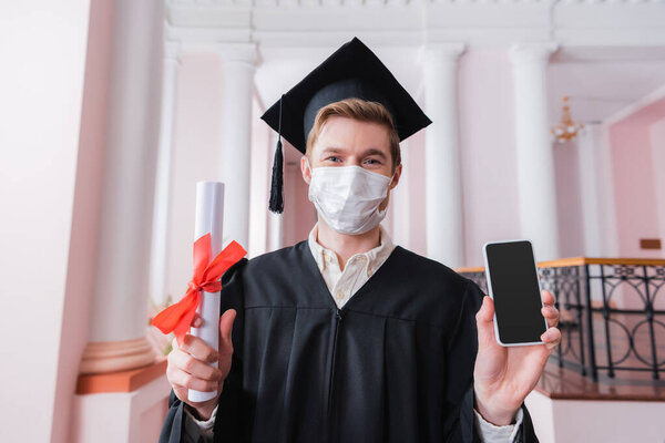 Graduate in medical mask holding smartphone and diploma 