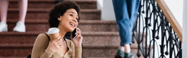 Alegre Estudiante Afroamericano Con Taza Papel Hablando Teléfono Inteligente Bandera —  Fotos de Stock