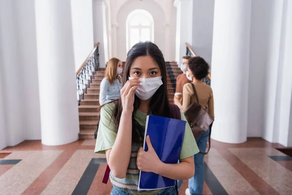 Ασιάτης Φοιτητής Ιατρική Μάσκα Κρατώντας Σημειωματάριο Στο Πανεπιστήμιο — Φωτογραφία Αρχείου
