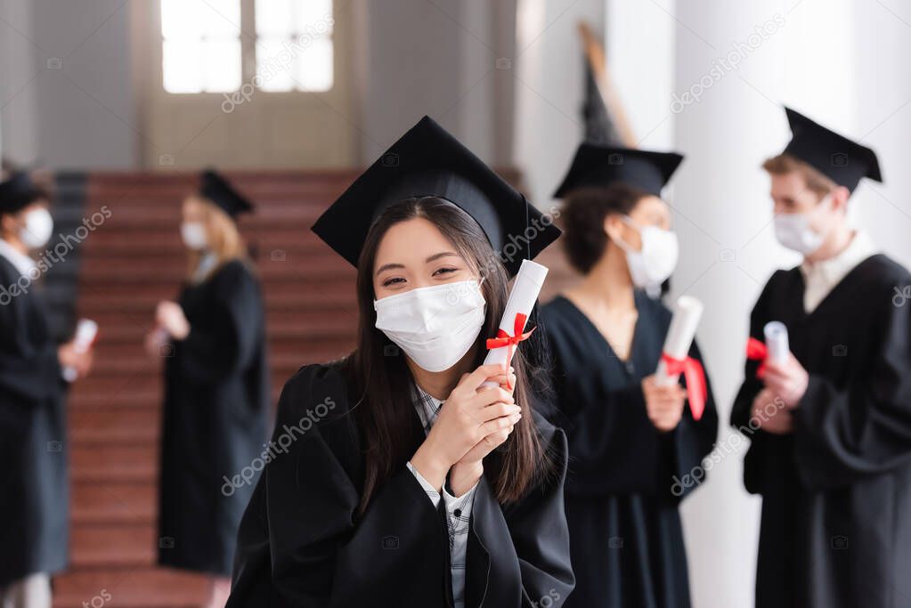 Asian bachelor in protective mask holding diploma in university 