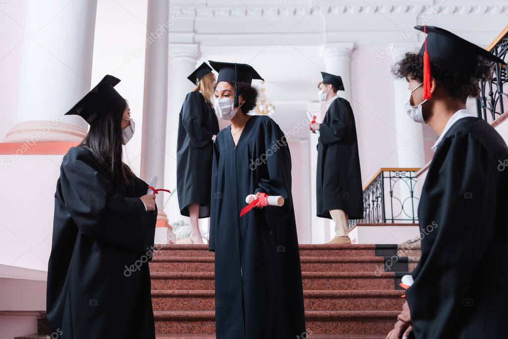 Multiethnic graduates in medical masks talking in university 