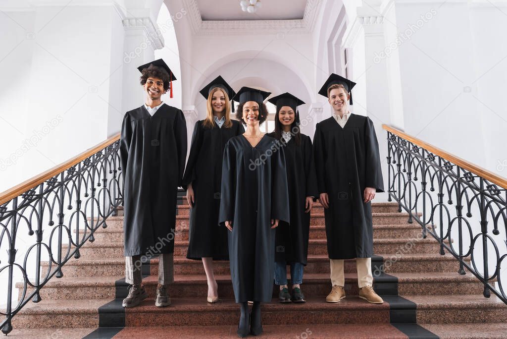 Happy interracial graduates looking at camera 