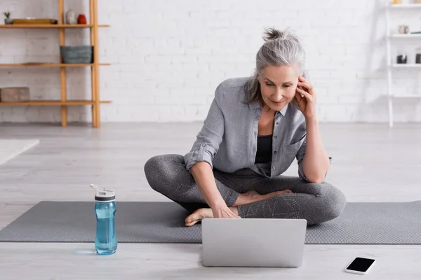 Middelaldrende Kvinne Sportsklær Som Sitter Lotusstilling Yogamatte Ser Nettundervisning Laptop – stockfoto