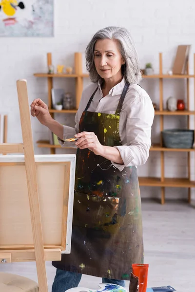 Middle Aged Artist Apron Holding Paintbrush While Painting Home — Stock Photo, Image