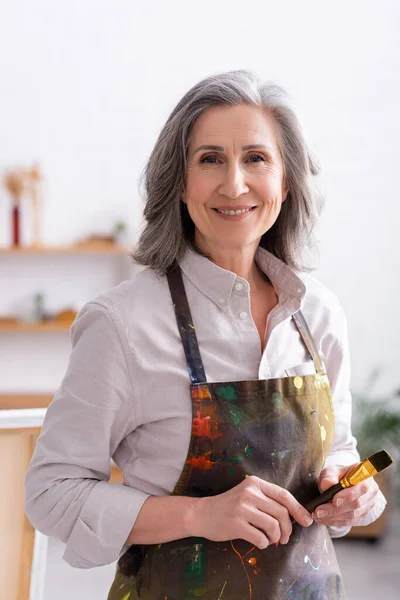 Cheerful Middle Aged Artist Apron Spills Holding Paintbrush — Stock Photo, Image