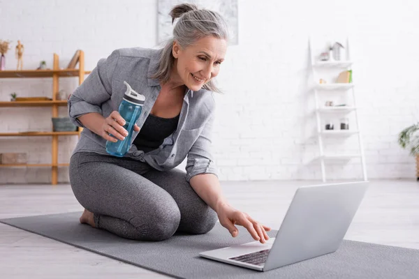 Sonriente Mujer Mediana Edad Sentado Colchoneta Fitness Sosteniendo Botella Deportes — Foto de Stock