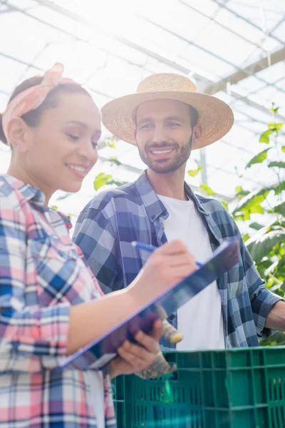 Alegre Mulher Afro Americana Escrevendo Prancheta Perto Agricultor Com Caixa — Fotografia de Stock