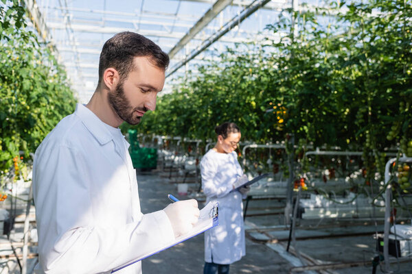 результаты записи инспектором качества в буфер обмена рядом с африканским американским коллегой на размытом фоне