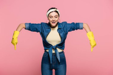 Sarı lastik eldivenli olumlu ev hanımı pembe üzerine izole edilmiş.