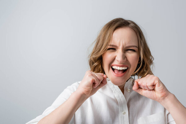 excited overweight woman in white shirt celebrating isolated on grey 