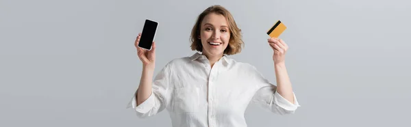 幸せなプラスサイズの女性はクレジットカードとスマートフォンを灰色のバナーに隔離し — ストック写真