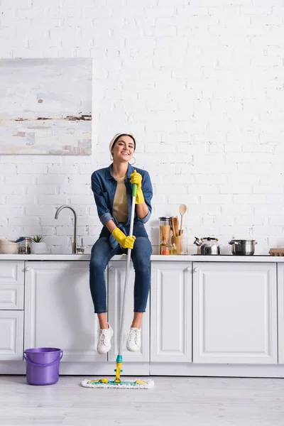 Leende Hemmafru Med Mopp Sittande Köksbänken — Stockfoto