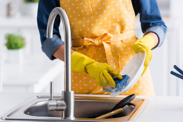 Cropped view of housewife washing plate in kitchen