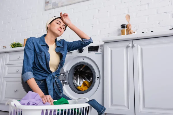 Müde Hausfrau Neben Korb Mit Kleidung Und Waschmaschine Küche — Stockfoto