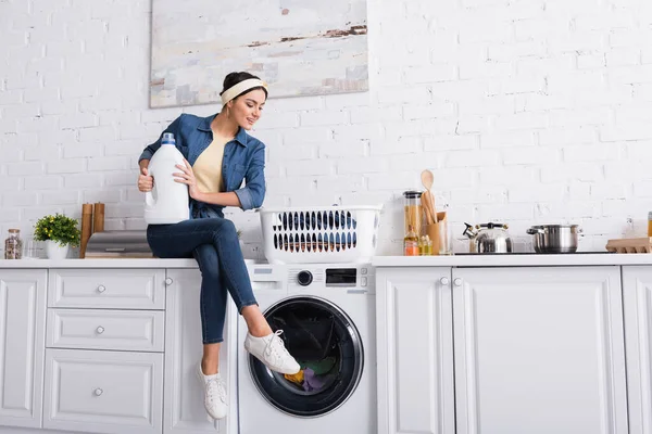 Fröhliche Hausfrau Mit Waschmittel Neben Waschmaschine Und Kleidung — Stockfoto