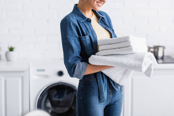 Cropped view of smiling housewife holding clean towels 
