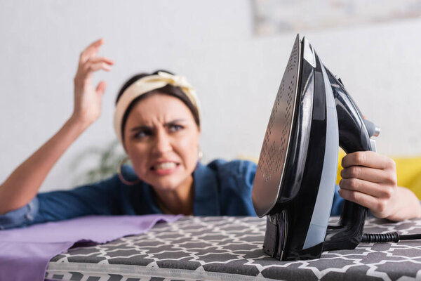 Железо рядом сердитая домохозяйка на размытом фоне 