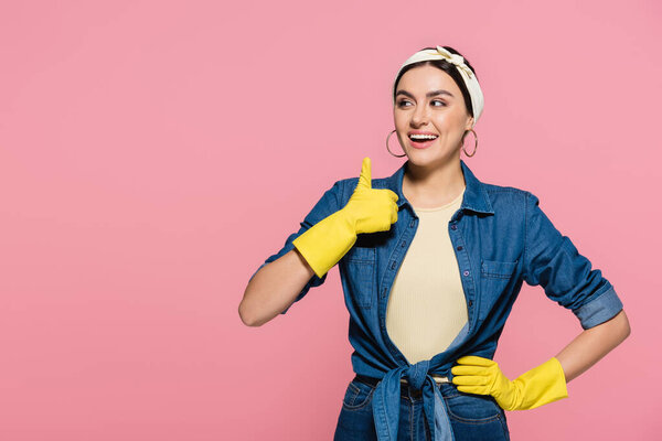 Cheerful housewife in rubber gloves showing like gesture isolated on pink