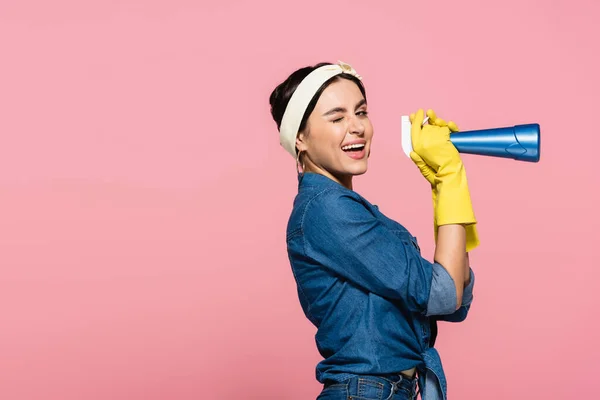 Glimlachende Huisvrouw Rubber Handschoenen Houden Wasmiddel Knipperen Camera Geïsoleerd Roze — Stockfoto