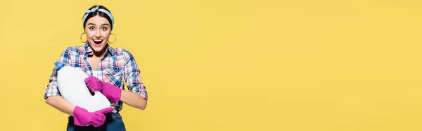 Podekscytowana Gospodyni Domowa Trzymająca Butelkę Detergentu Izolowaną Żółtym Sztandarze — Zdjęcie stockowe