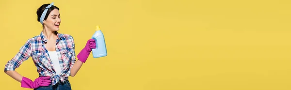 Домохозяйка Резиновых Перчатках Держит Бутылку Моющего Средства Изолированы Желтый Баннер — стоковое фото