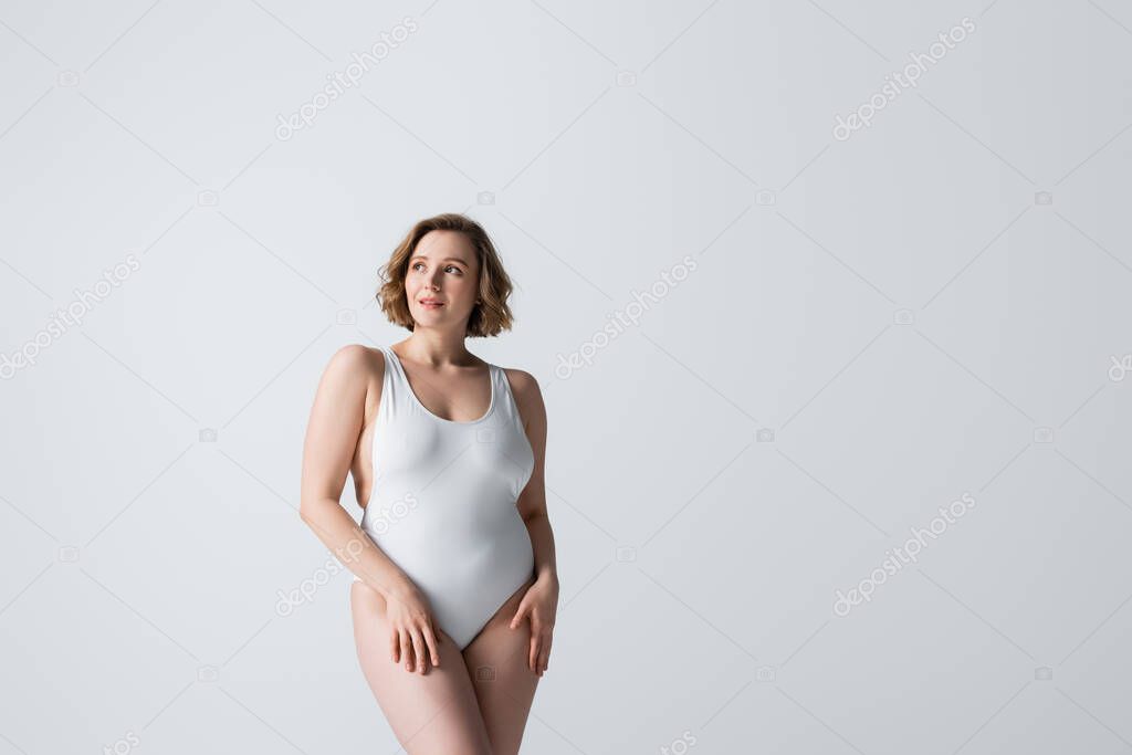 dreamy overweight woman in swimwear looking away isolated on white