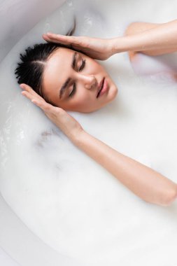 Süt banyosu yaparken saçlarına dokunan şehvetli kadın manzarası