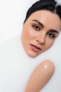 Süt banyosu yaparken kameraya bakan baştan çıkarıcı kadın.