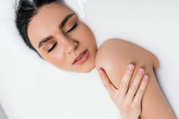 乳浴をしながら目を閉じて肩に触れる官能的な女性 — ストック写真