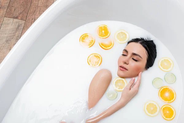 Bonita Mulher Tocando Rosto Enquanto Toma Banho Leite Com Frutas — Fotografia de Stock