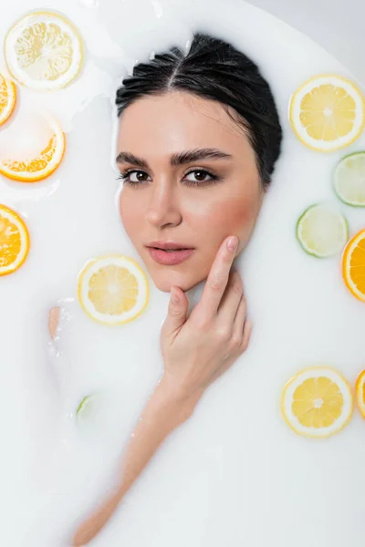 Donna Sensuale Guardando Fotocamera Toccando Viso Mentre Bagno Nel Latte — Foto Stock