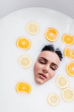 Süt içinde limon ve portakal dilimleriyle yıkanan kadın manzarası.