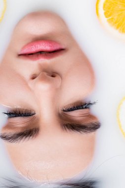 Banyodaki kadın yüzünü sütle ve dilimlenmiş portakalla kapat.